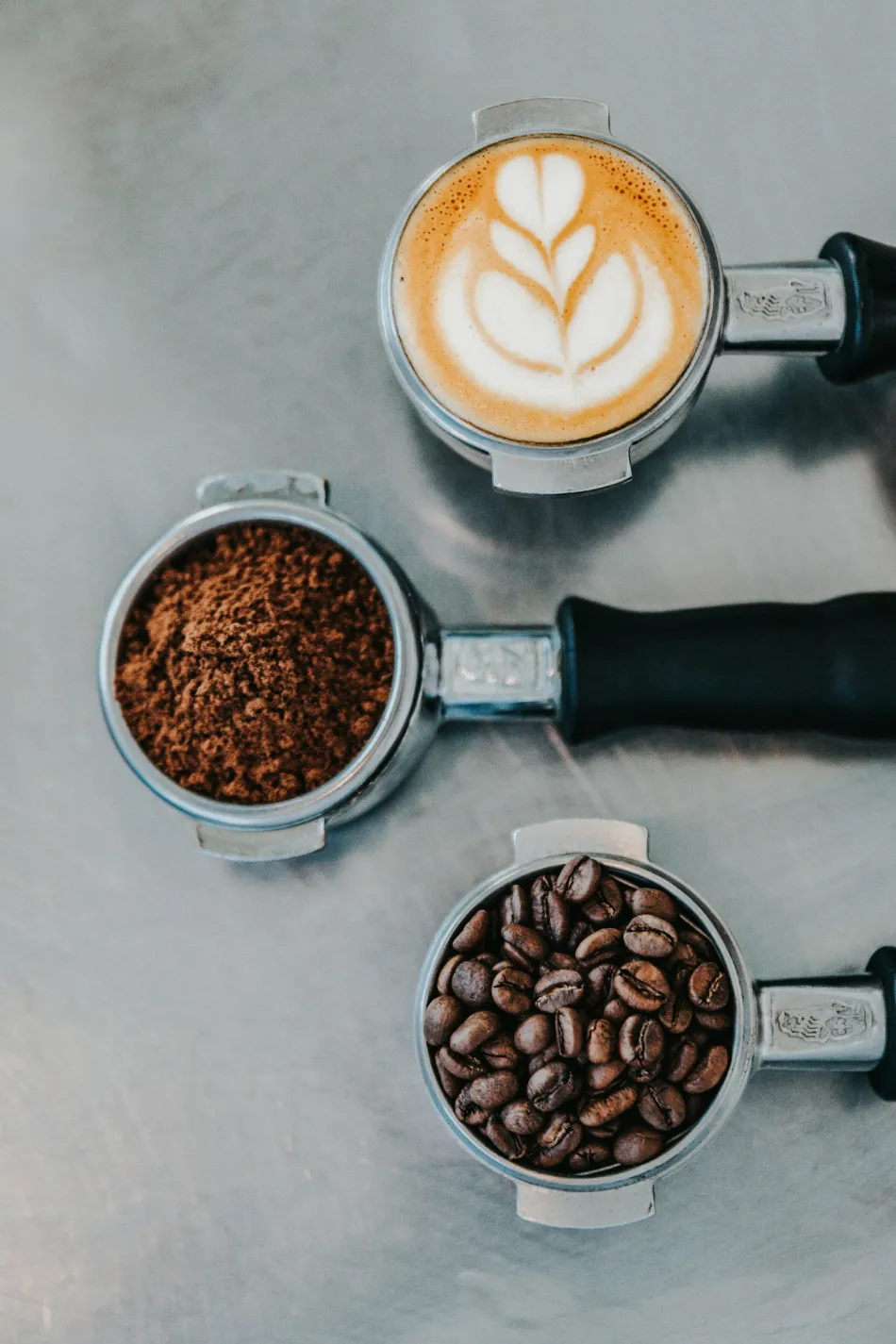 Trzy kolby z kawą — gotowe espresso z mlekiem, świeżo zmielona kawa i całe ziarna